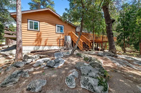 a backyard of a house with large trees and wooden fence