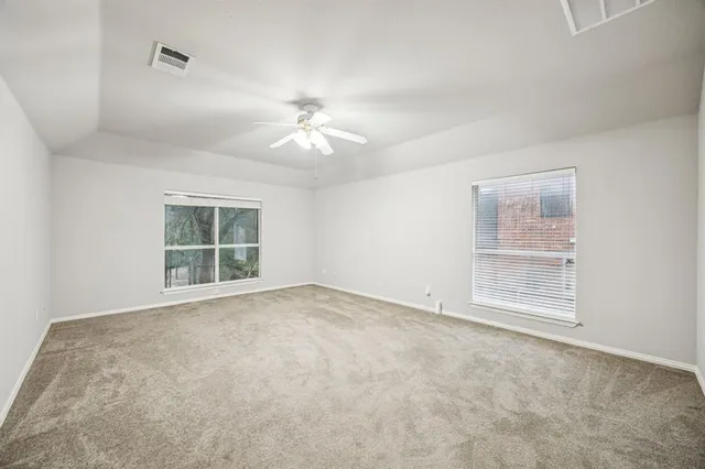 an empty room with windows and chandelier fan