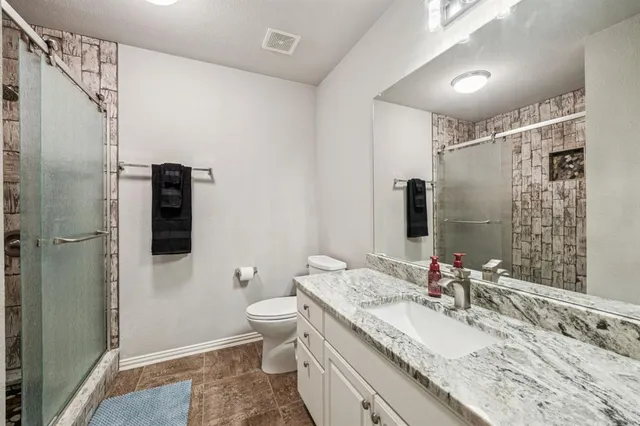 a bathroom with a granite countertop sink toilet and shower