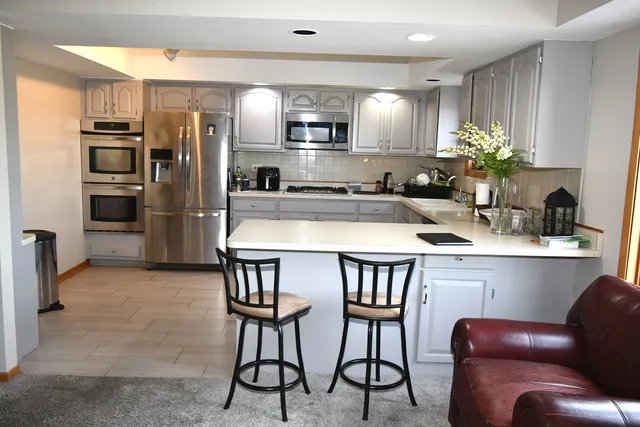 a kitchen with stainless steel appliances a table chairs refrigerator and microwave