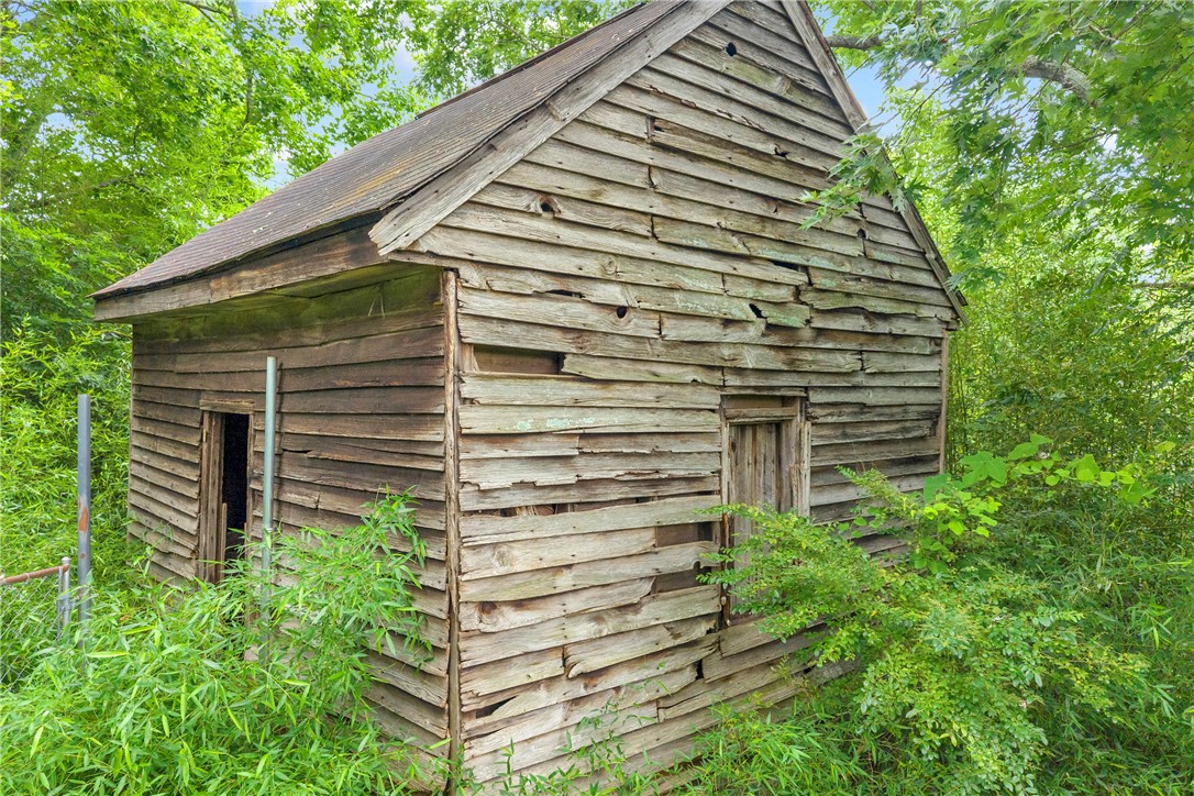 200 Chenault Road Townville, SC 29689 - Photo 38 of 47 A rustic outbuilding with weathered wood siding sits amidst vibrant green foliage.
