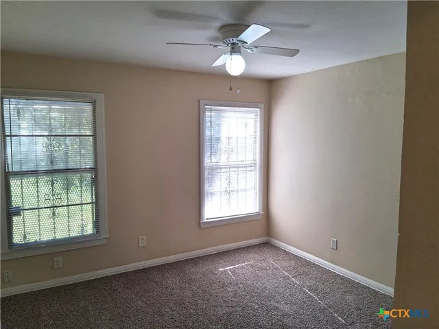 an empty room with windows and fan