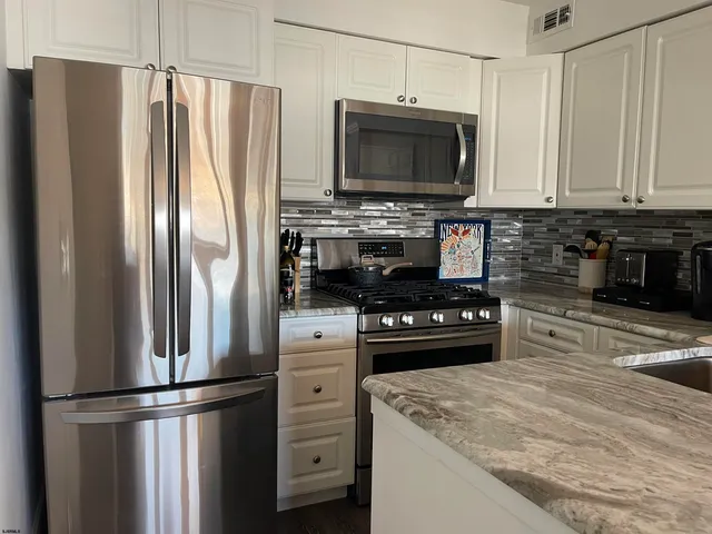 a kitchen with kitchen island a counter top space stainless steel appliances and cabinets