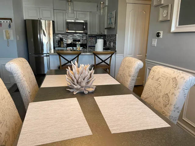 a kitchen with stainless steel appliances kitchen island granite countertop a refrigerator oven a sink a dining table and chairs