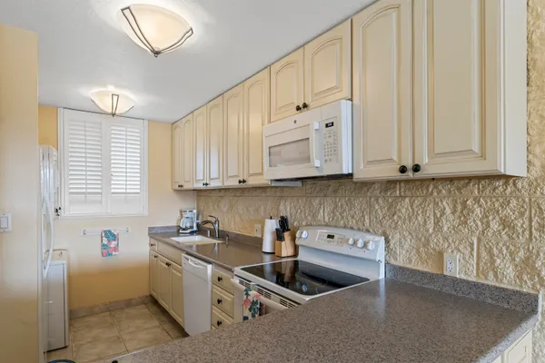 a kitchen with granite countertop a sink a stove and cabinets