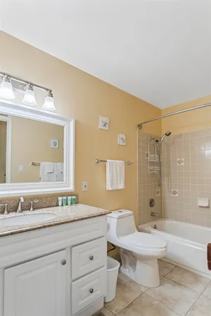 a bathroom with a granite countertop sink mirror vanity bathtub and toilet