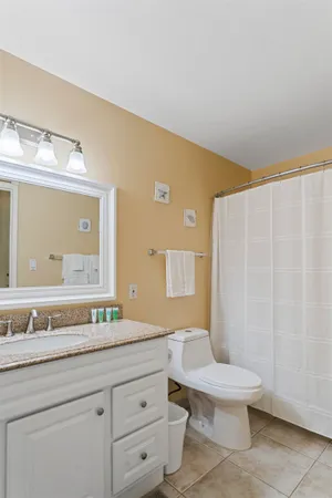 a bathroom with a granite countertop sink a toilet and a mirror