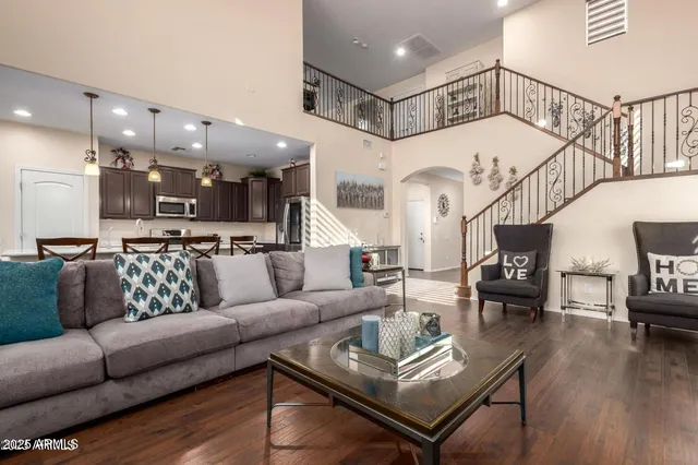 a living room with furniture kitchen view and a wooden floor