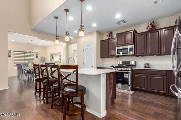 a kitchen with stainless steel appliances a table chairs microwave and sink