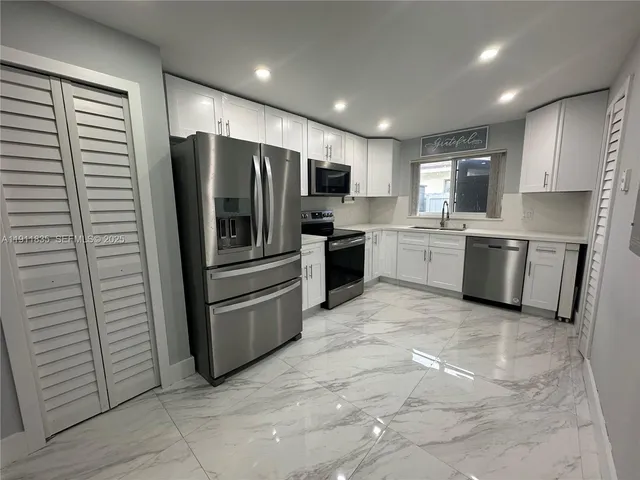 a kitchen with stainless steel appliances granite countertop a refrigerator and a stove