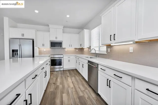 a kitchen with kitchen island white cabinets sink and stainless steel appliances