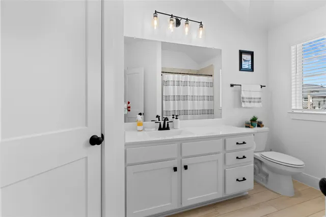 a bathroom with a double vanity sink a toilet and a window