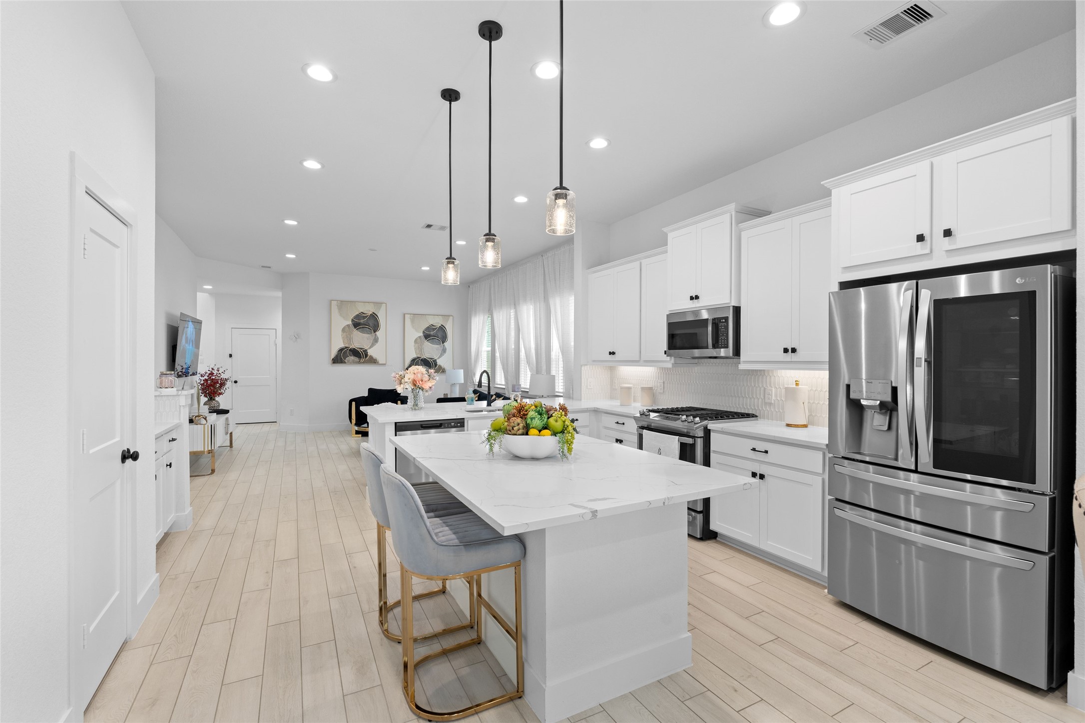 17735 Tree Of Heaven Conroe, TX 77385 - Photo 8 of 35 a kitchen with stainless steel appliances a refrigerator a stove a sink dishwasher and a dining table with wooden floor