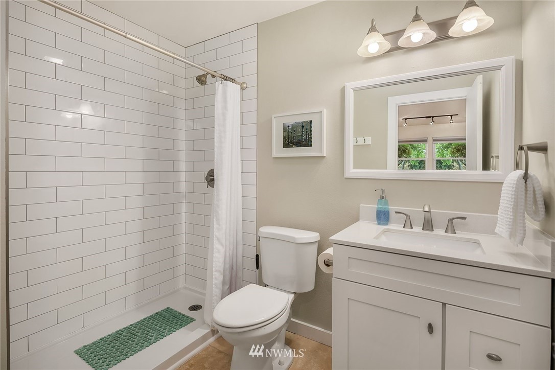 355 North 75th Street Seattle, WA 98103 - Photo 28 of 32 a bathroom with a granite countertop toilet sink and mirror