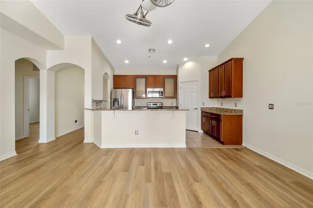 a view of kitchen with stainless steel appliances granite countertop a stove top oven a sink dishwasher and a microwave oven with wooden floor