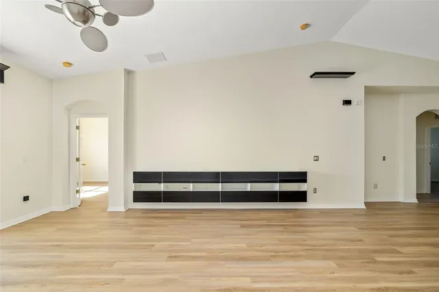 a view of an empty room with wooden floor and windows