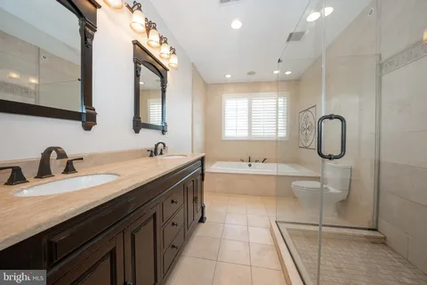 a spacious bathroom with a granite countertop sink mirror and bathtub