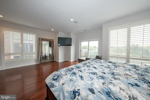 a large bedroom with wooden floor and large window