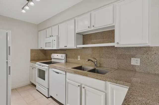 a kitchen with white cabinets and white appliances