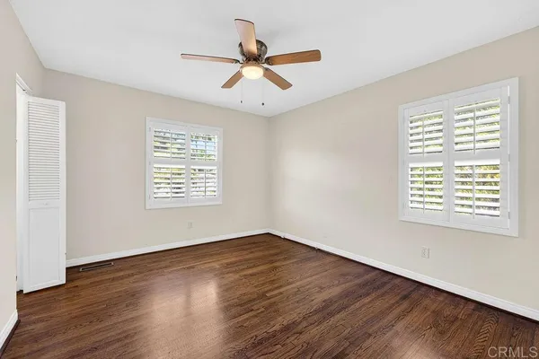 an empty room with wooden floor chandelier fan and closet area