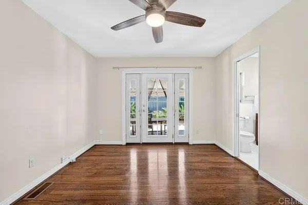 an empty room with wooden floor and ceiling fan