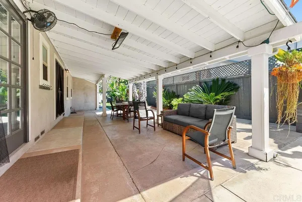 a view of a patio with table and chairs potted plants and floor to ceiling window