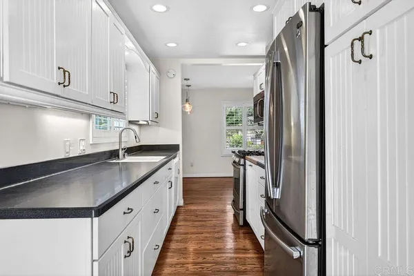 a large kitchen with stainless steel appliances a refrigerator a sink and white cabinets