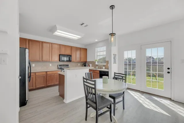 a kitchen with a table chairs refrigerator and cabinets