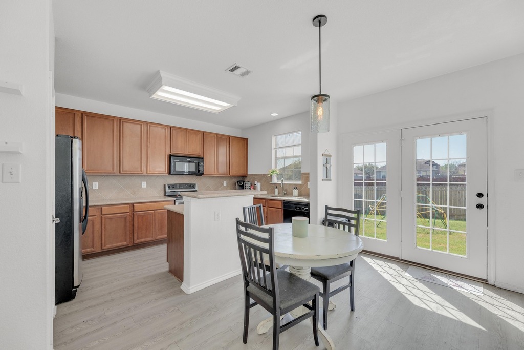 150 Mistletoe Lane Kyle, TX 78640 - Photo 8 of 35 a kitchen with a table chairs refrigerator and cabinets