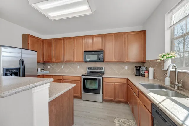 a kitchen with stainless steel appliances granite countertop a sink stove microwave and refrigerator