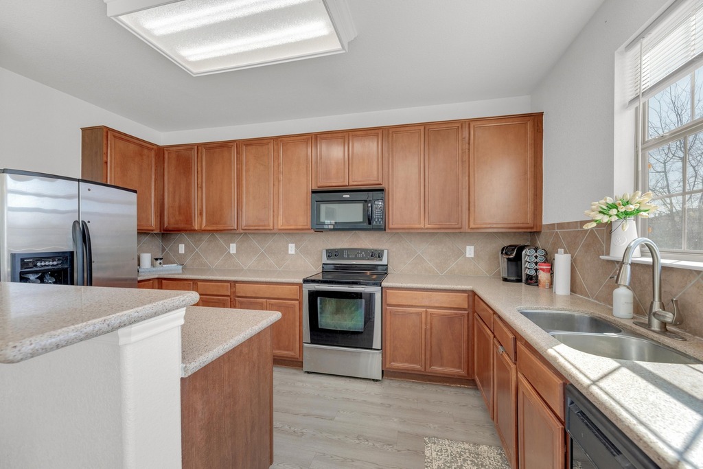 150 Mistletoe Lane Kyle, TX 78640 - Photo 10 of 35 a kitchen with stainless steel appliances granite countertop a sink stove microwave and refrigerator
