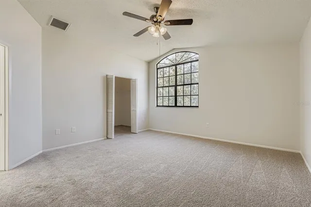 an empty room with windows and fan