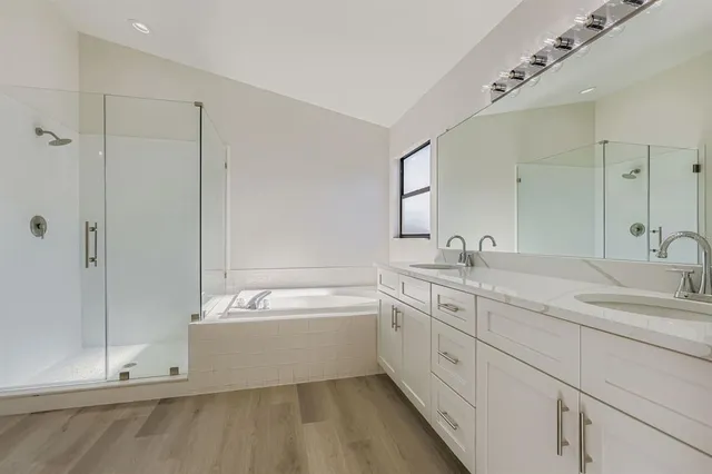 a spacious bathroom with a double vanity sink mirror and bathtub