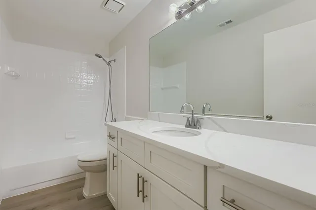 a bathroom with a granite countertop sink a toilet and a bathtub