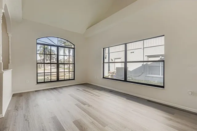 an empty room with wooden floor and windows