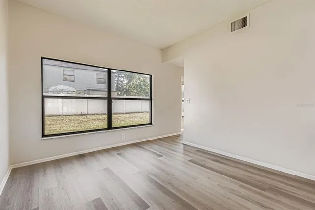 an empty room with wooden floor and windows