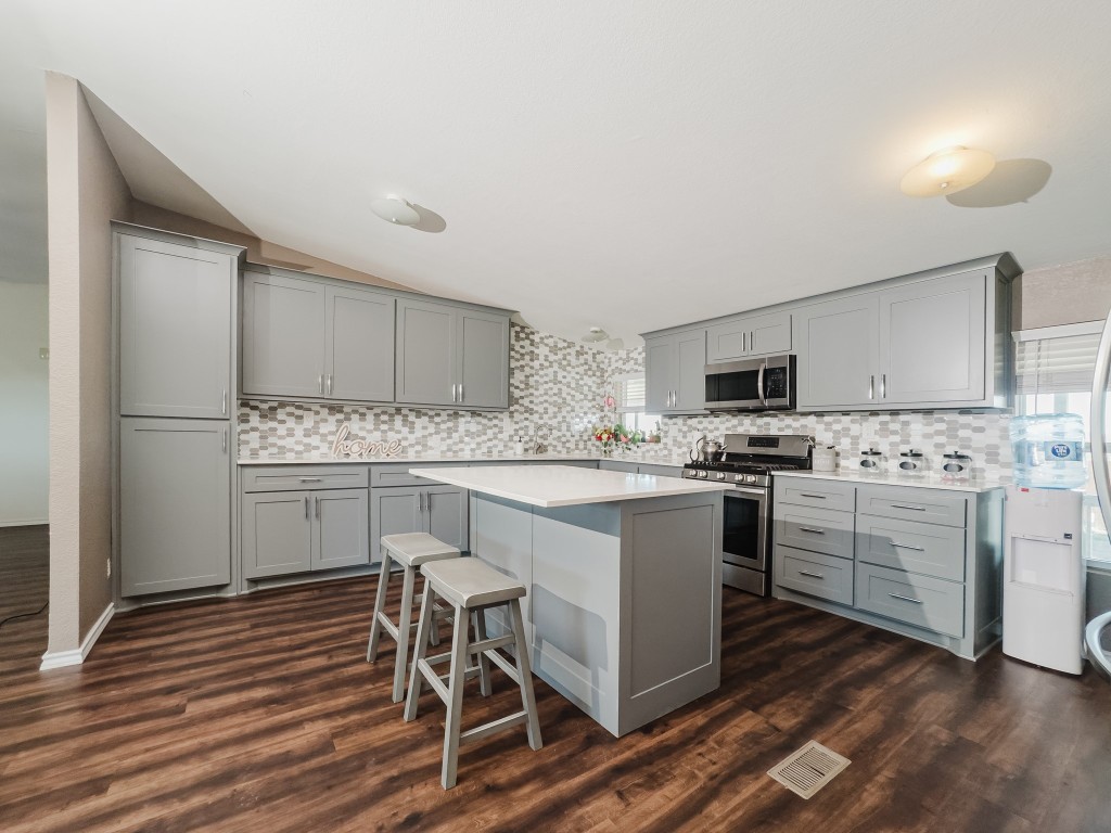 2709 County Road 463 Elgin, TX 78621 - Photo 18 of 40 Kitchen with gray cabinets, a kitchen breakfast bar, vaulted ceiling, appliances with stainless steel finishes, and a center island