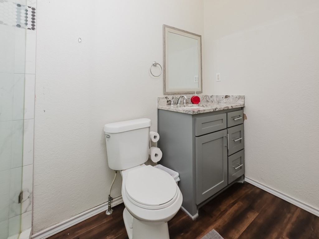 2709 County Road 463 Elgin, TX 78621 - Photo 32 of 40 Full bathroom with vanity, dark wood finished floors, a textured wall, and a shower