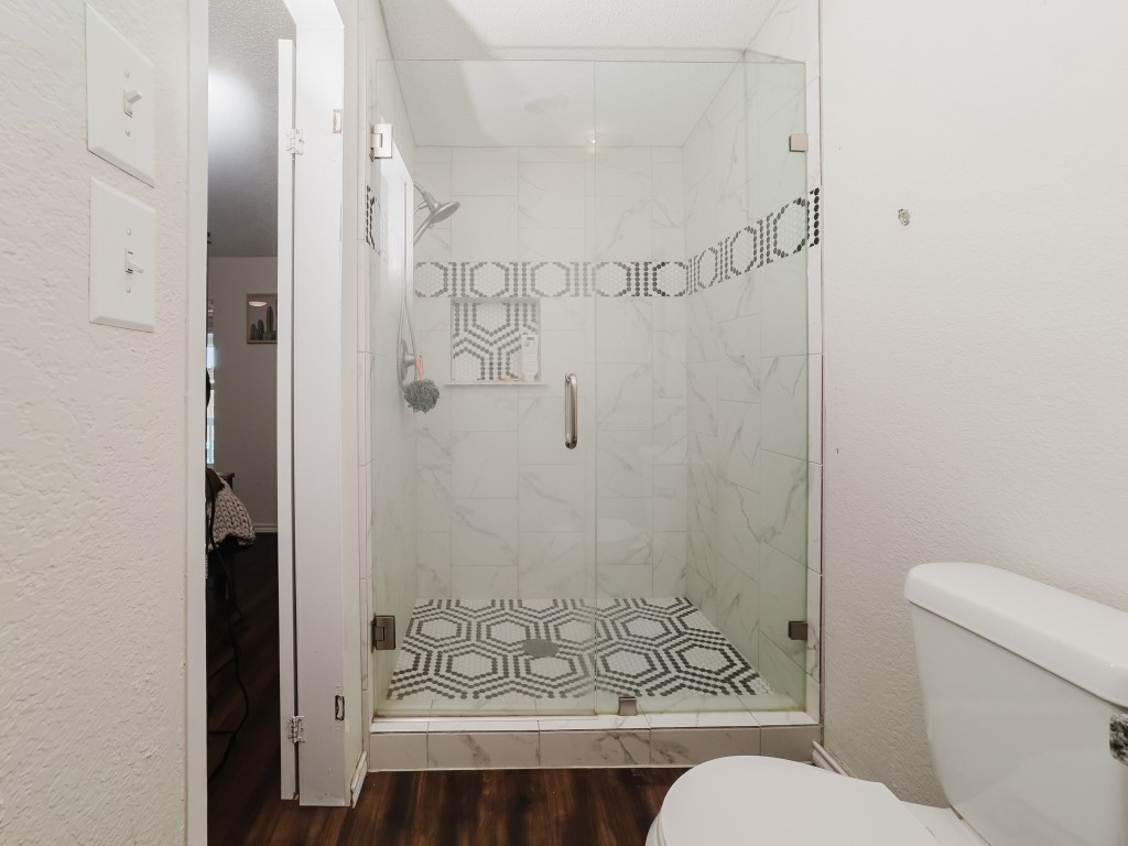 2709 County Road 463 Elgin, TX 78621 - Photo 33 of 40 Bathroom featuring a textured wall, a shower stall, and dark wood-style floors