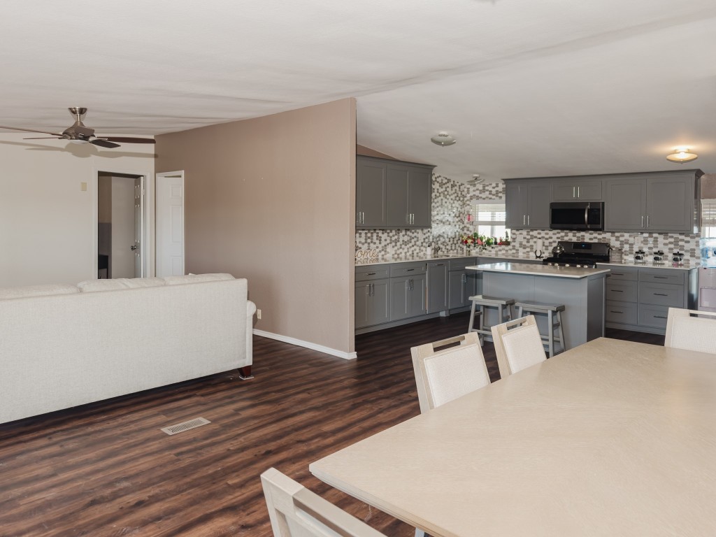 2709 County Road 463 Elgin, TX 78621 - Photo 40 of 40 Kitchen featuring gray cabinetry, a breakfast bar area, open floor plan, stainless steel microwave, and light countertops