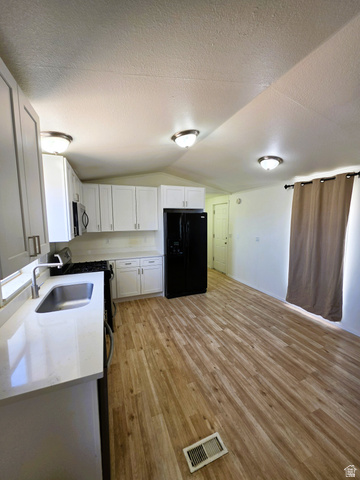 1604 180 East Tooele, UT 84074 - Photo 5 of 16 Open-concept kitchen featuring white cabinetry, light-toned countertops, and wood-finish flooring