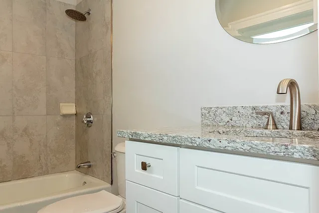 a bathroom with a granite countertop sink a toilet and bathtub