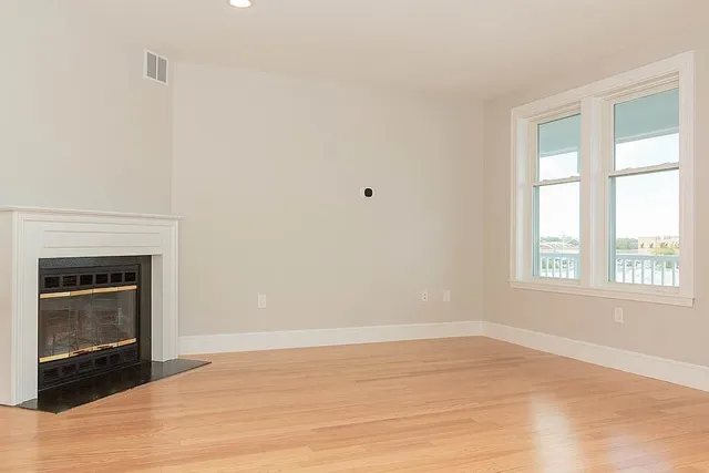 a view of an empty room with a window and a fireplace
