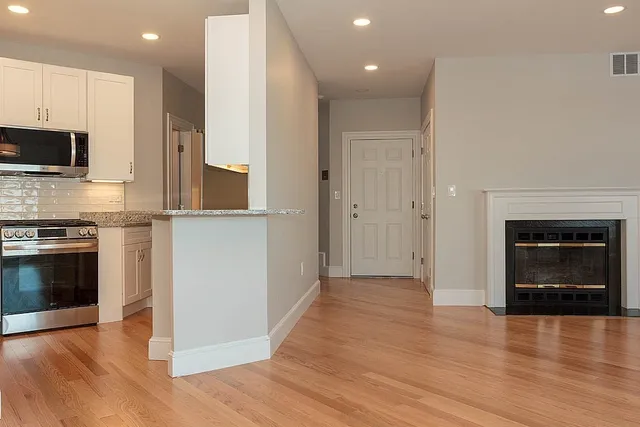 a view of a kitchen with wooden floor and a fireplace