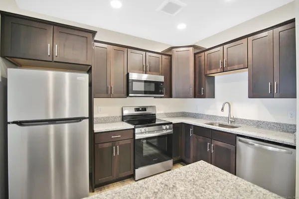 a kitchen with stainless steel appliances granite countertop a refrigerator stove a sink dishwasher and microwave
