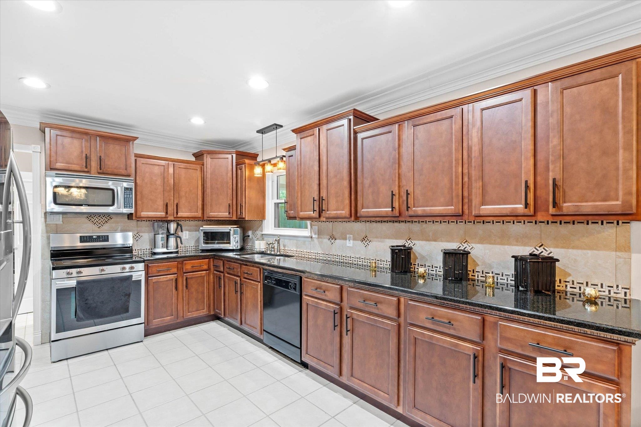 101 Ann Street Daphne, AL 36527 - Photo 11 of 38 Kitchen featuring extensive wood cabinetry, black countertops, stainless steel appliances, a tiled backsplash, and recessed lighting