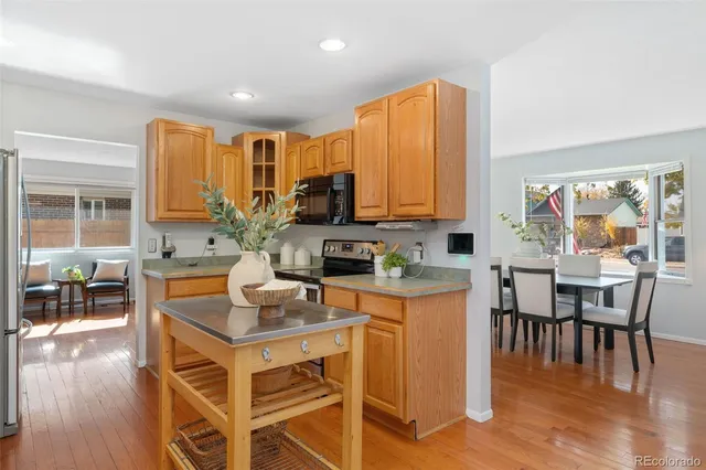 a kitchen with stainless steel appliances a stove a sink a microwave a dining table and chairs