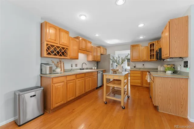 a kitchen with stainless steel appliances kitchen island granite countertop wooden cabinets and a refrigerator