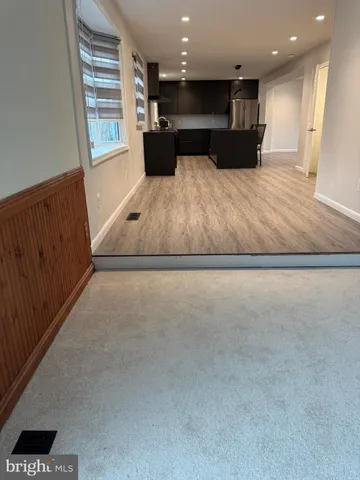 a view of kitchen with kitchen island a sink wooden floor and black appliances