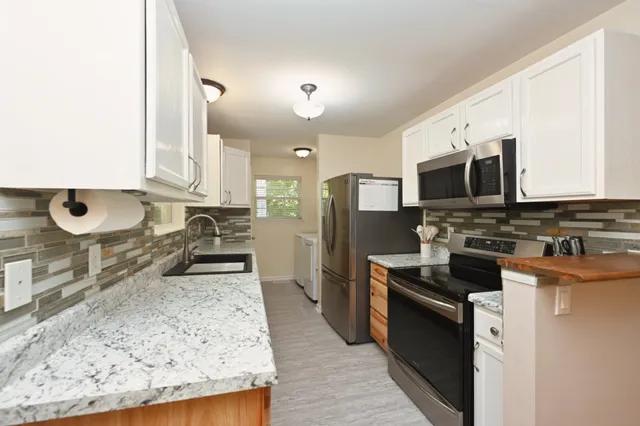 a kitchen with stainless steel appliances granite countertop a stove a sink and a microwave